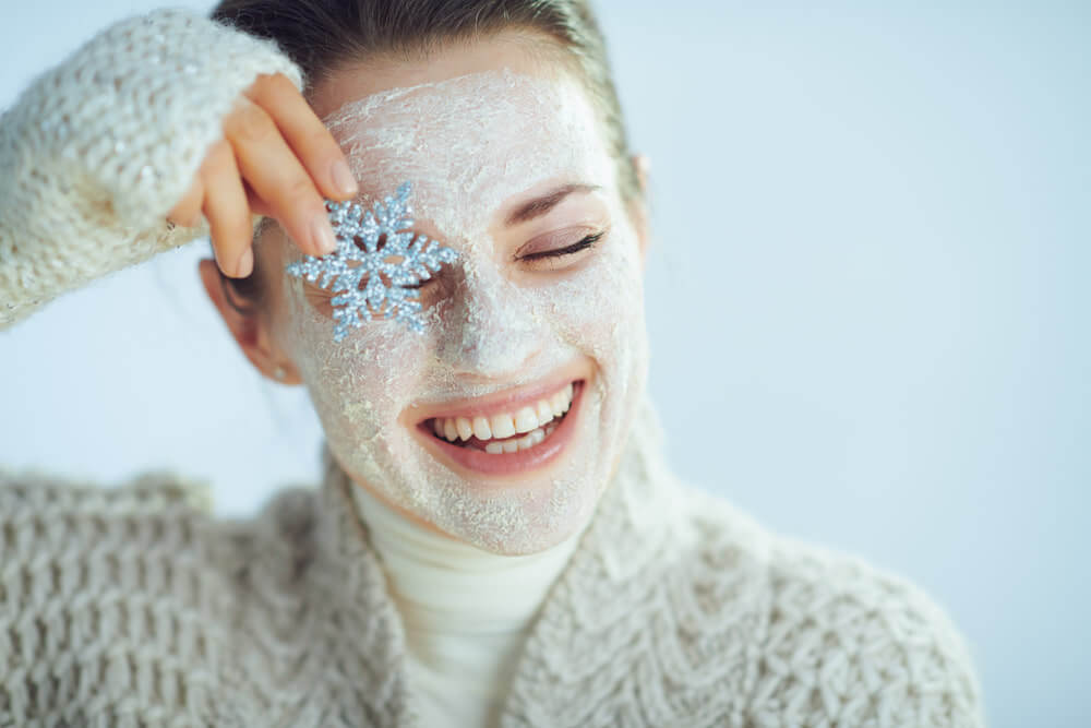 imagen de una mujer cuidando su piel en invierno con un copo de nieve